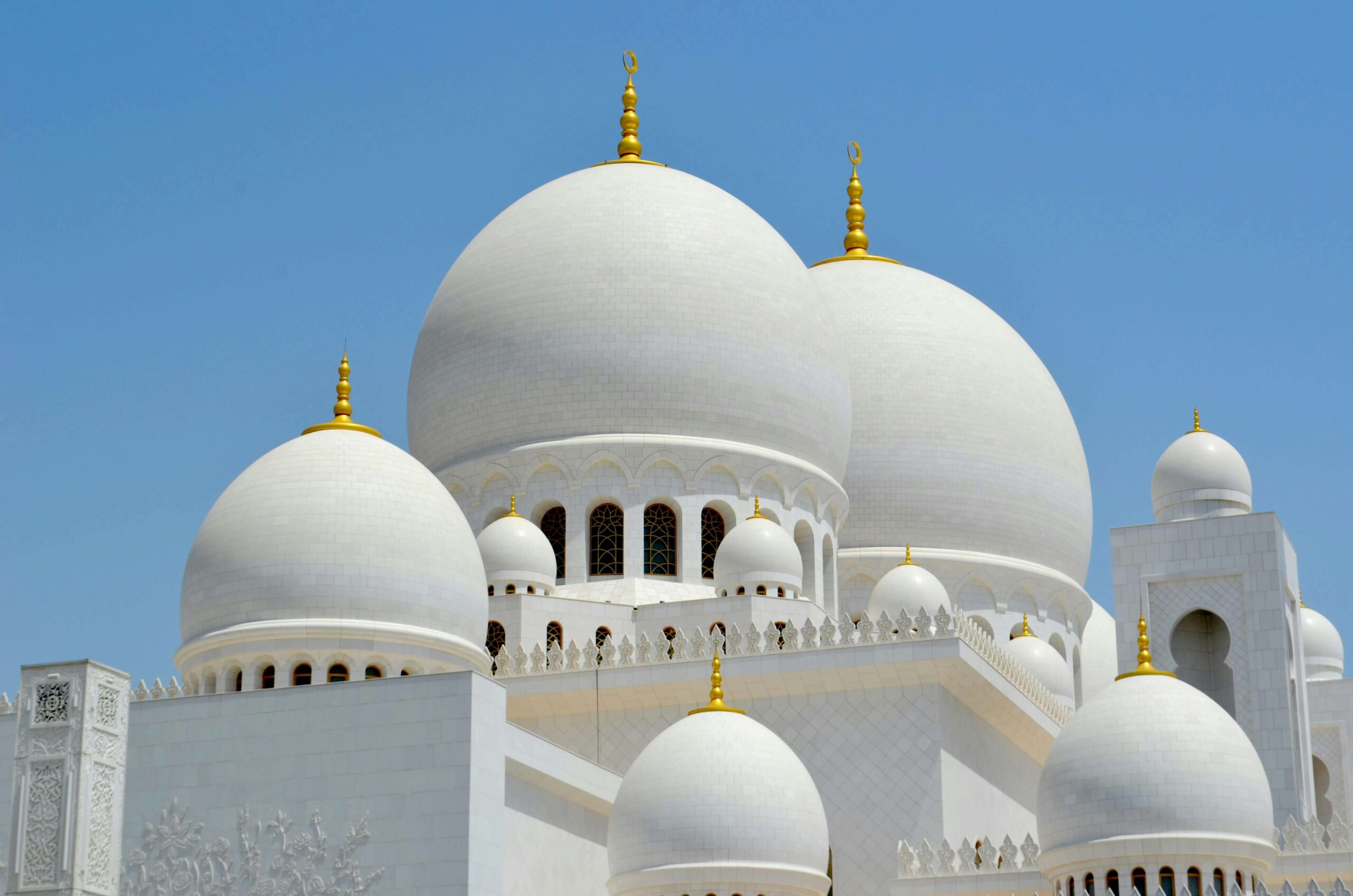 Sheikh Zayed Grand Mosque white domes under clear blue sky in Abu Dhabi, UAE